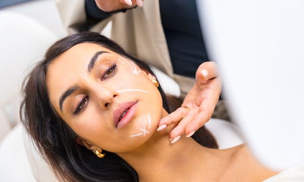Woman with correcting lines painted on the face in a beautician clinic