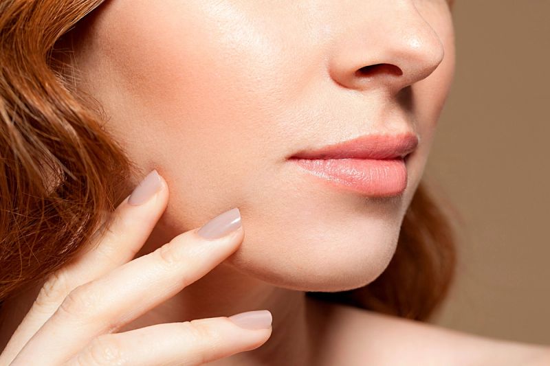 lower face photo of woman touching jawline