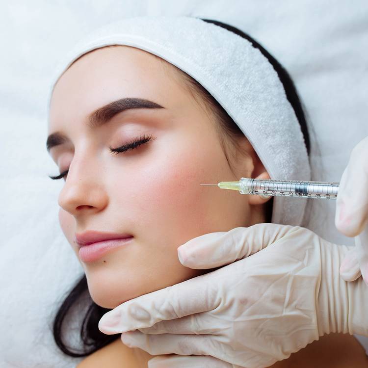 Smile lifting and lip augmentation. Beautician doctor hands doing beauty procedure to female face with syringe. Young woman's mouth contouring with filler injection. Marionette lines treatment.