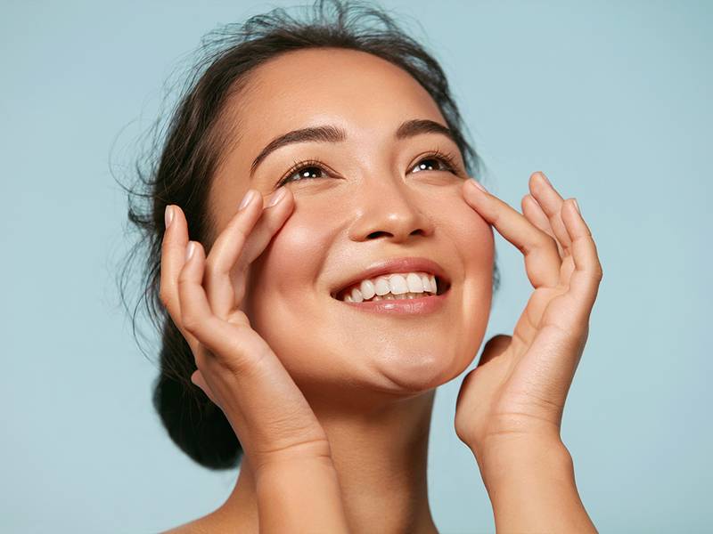woman touching her bare face and smiling