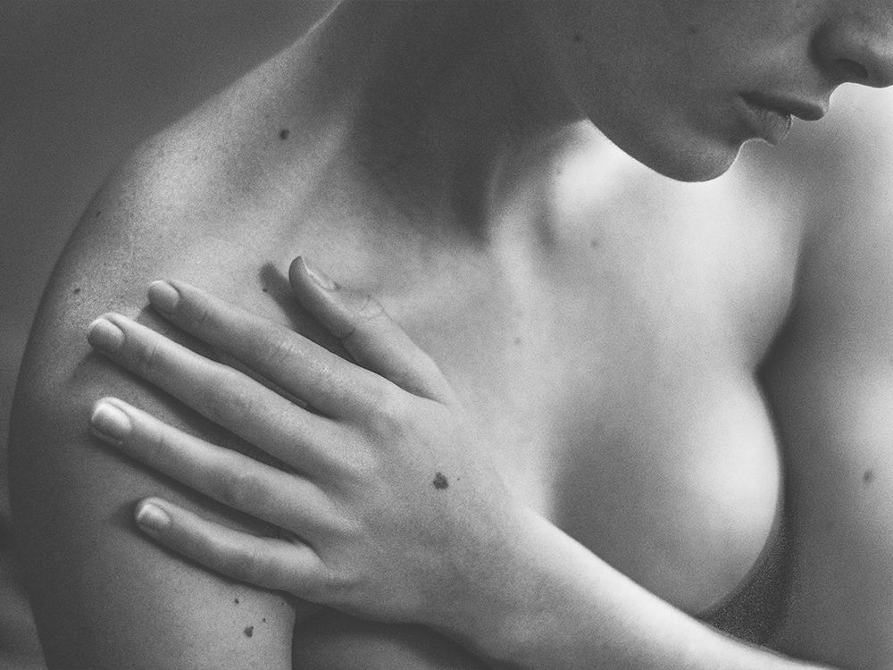 black and white photo of woman's chest with hand over chest