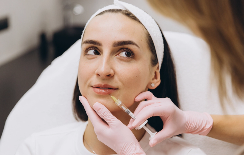 Close-up of a woman receiving a lip filler injection from a gloved provider