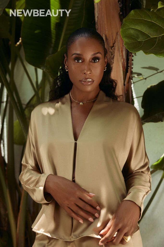 Issa Rae in gold silk outfit against palm background