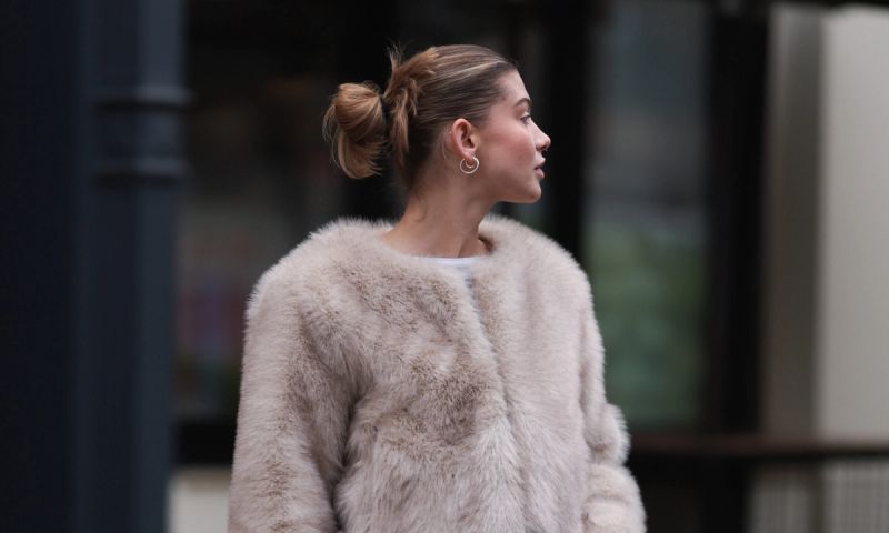 Sophia Geiss is seen wearing two different-sized gold hoop earrings, a silver nose ring, a cropped beige faux fur jacket with wide sleeves from Meotine, underneath a cropped white top from Miu Miu, a brown logo-patterned “Speedy“ bag from Louis Vuitton, a silver ring, wide-legged jeans from COS, and beige suede platform shoes with decorative seams from Ugg on November 22, 2024 in Berlin, Germany.