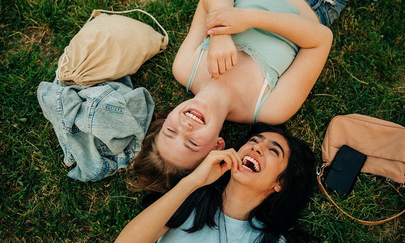Cheerful teenage girls lying together at park