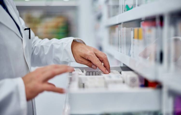 Pharmacist selecting medication from a pharmacy shelf