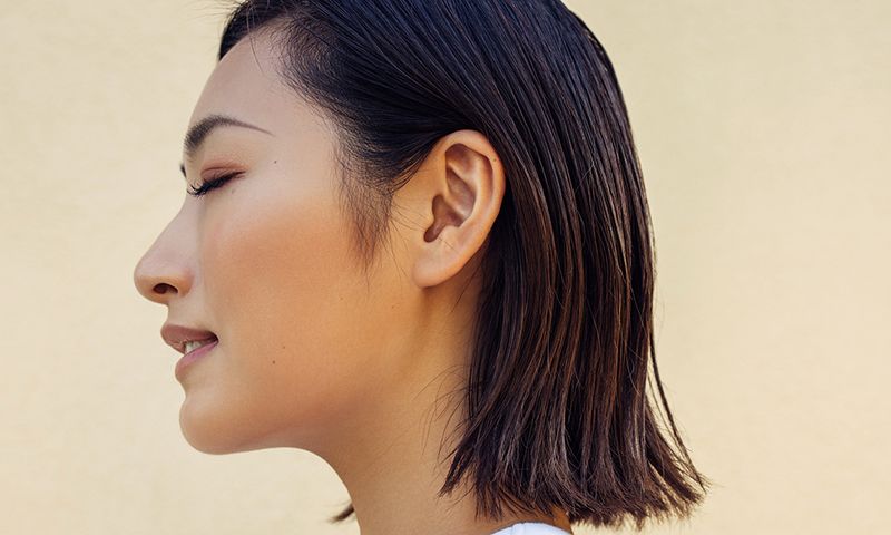 A serene profile portrait of a woman with short hair and closed eyes, conveying a sense of peace and contemplation. The soft lighting and clean background emphasize her relaxed expression, highlighting the quiet elegance of the moment. The image captures a natural and minimalist aesthetic, with a focus on simplicity and inner calm.