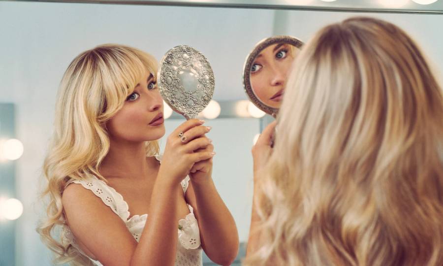 Sabrina Carpenter looking at hair in mirror