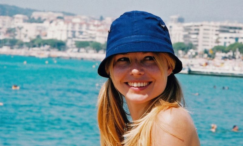 woman by the water smiling and wearing a bucket hat