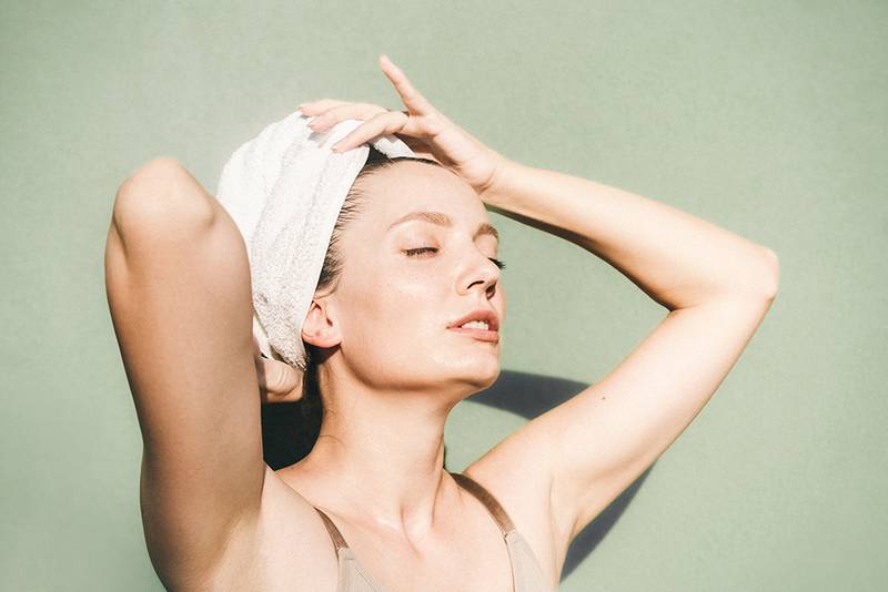 woman with hair towel and fresh clean skin against green background