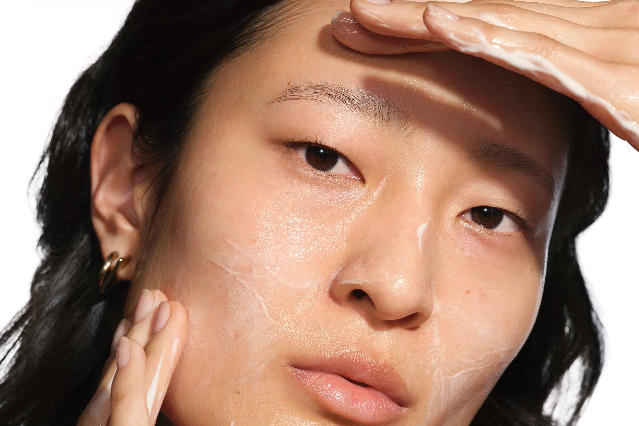Asian woman washign face with cleanser