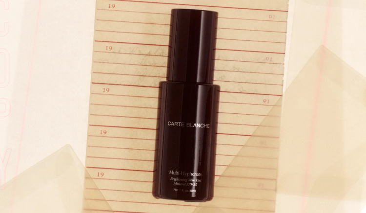 A dark oxblood glass bottle of Carte Blanche's Multi-Hyphenate Brightening Skin Tint Mineral SPF 35 lies on a lined notebook page marked with faded "19" date numbers.