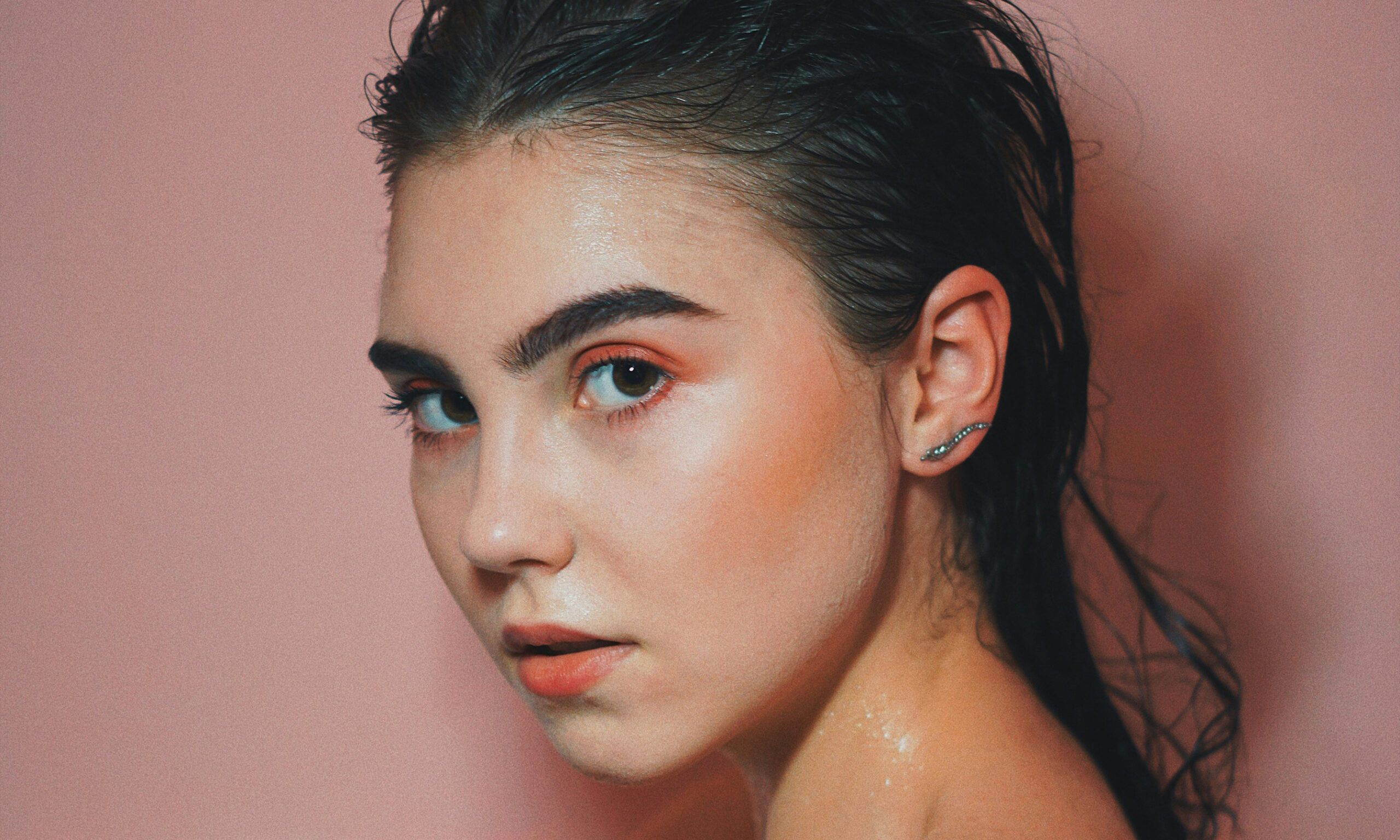 Woman with wet slicked back hair in bathtub