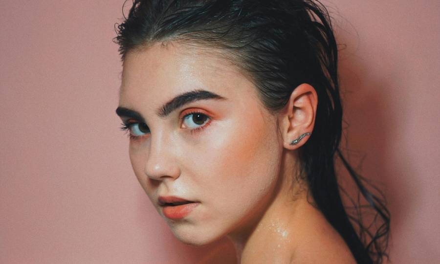 Woman with wet slicked back hair in bathtub