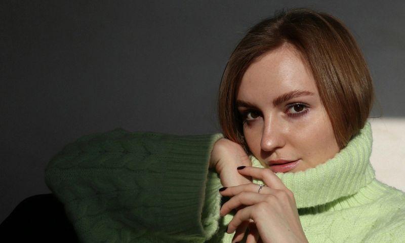 woman in green turtleneck sitting in sun spotlight