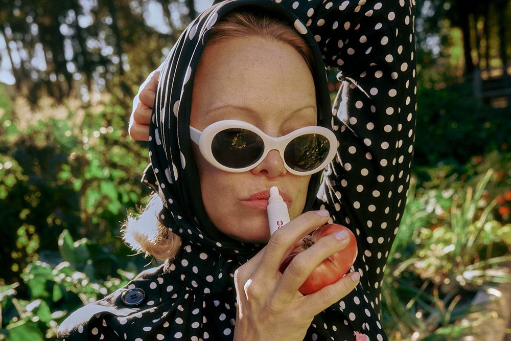 Pamela Anderson in sunglasses applying Sonsie lip balm