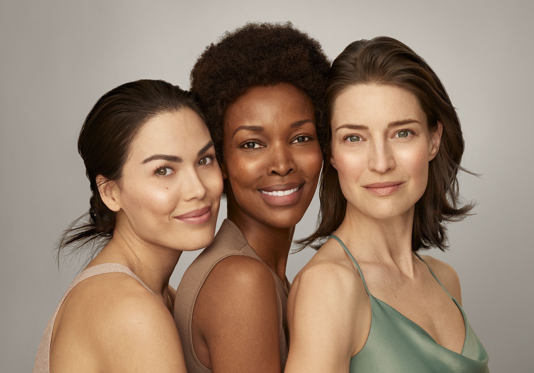 A group of three multicultural women smiling at the camera