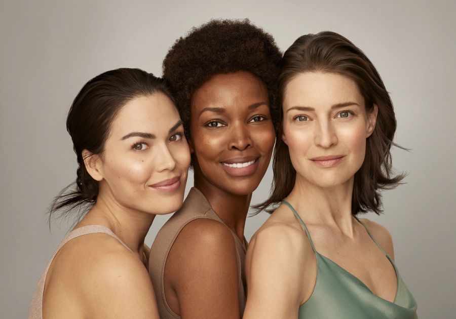 A group of three multicultural women smiling at the camera