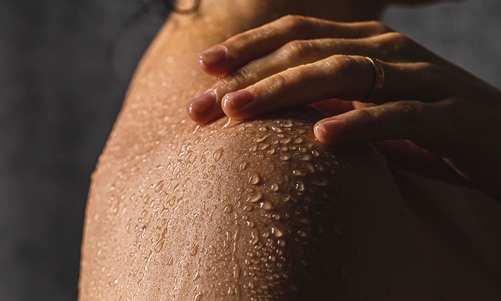 Detail of woman's shoulder with hand while taking a shower.