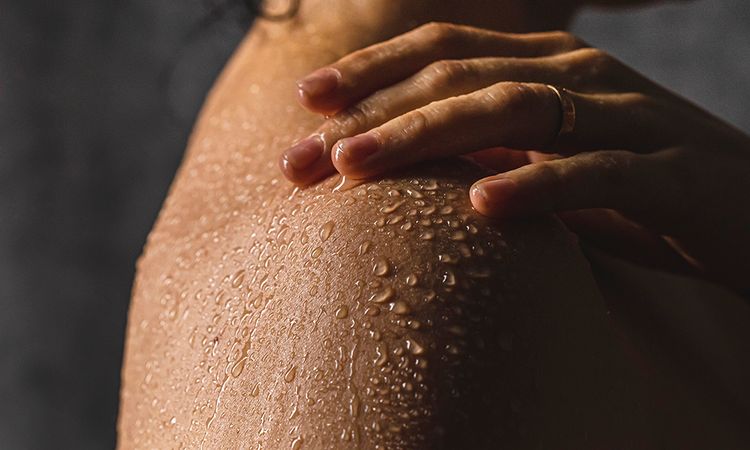 Detail of woman's shoulder with hand while taking a shower.