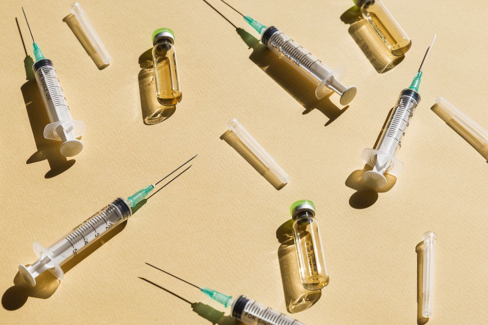 Syringe and Vaccine against yellow background