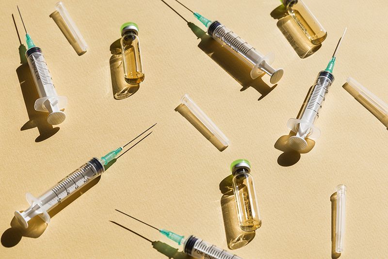 Syringe and Vaccine against yellow background