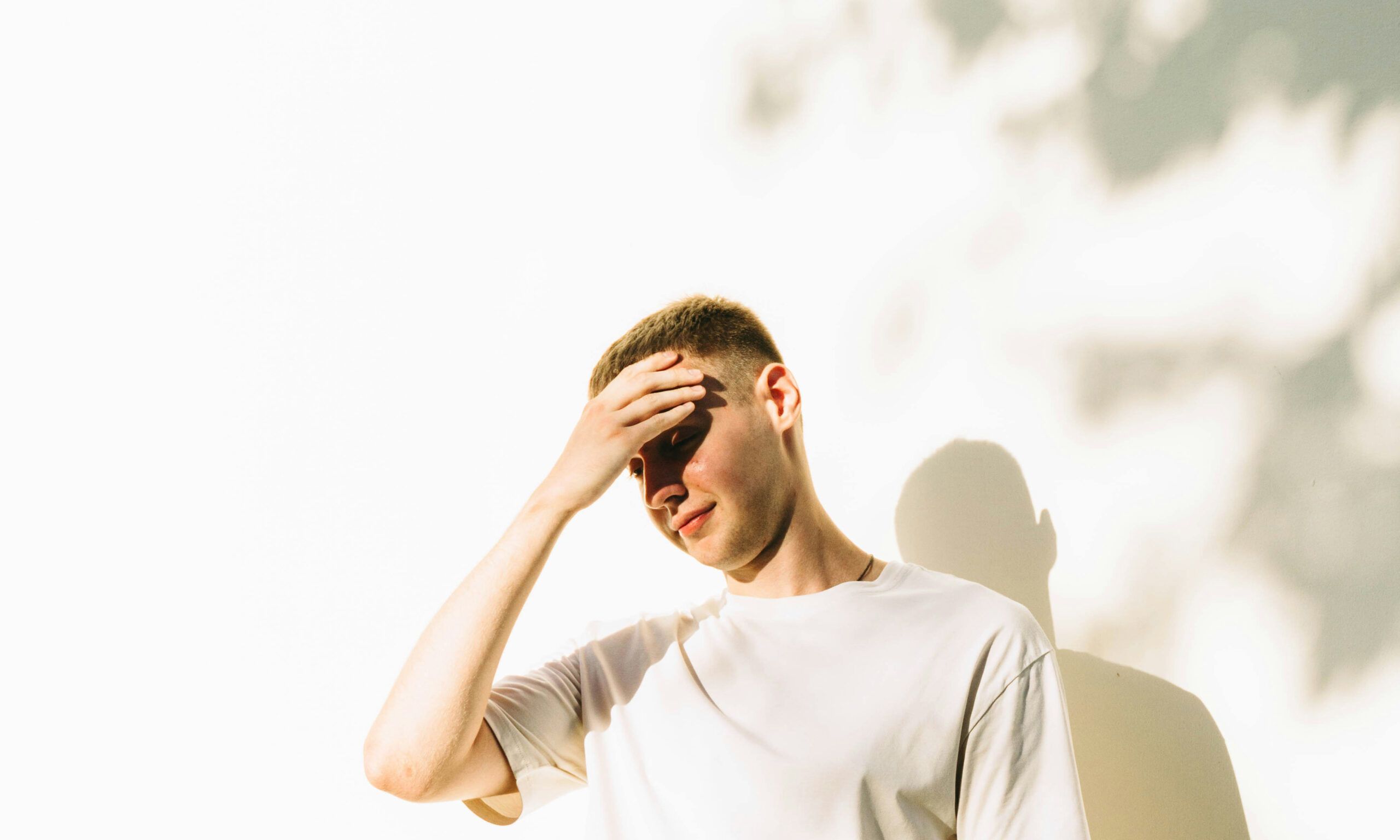 Man in sunlight with hand on his forehead