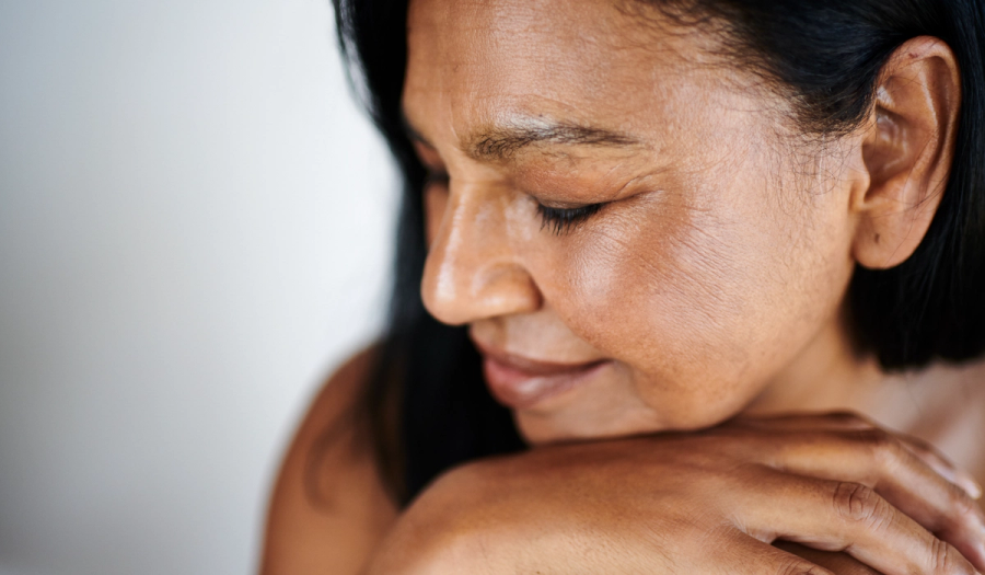 Woman with mature skin and dark hair rests her chin on her hands, eyes closed.