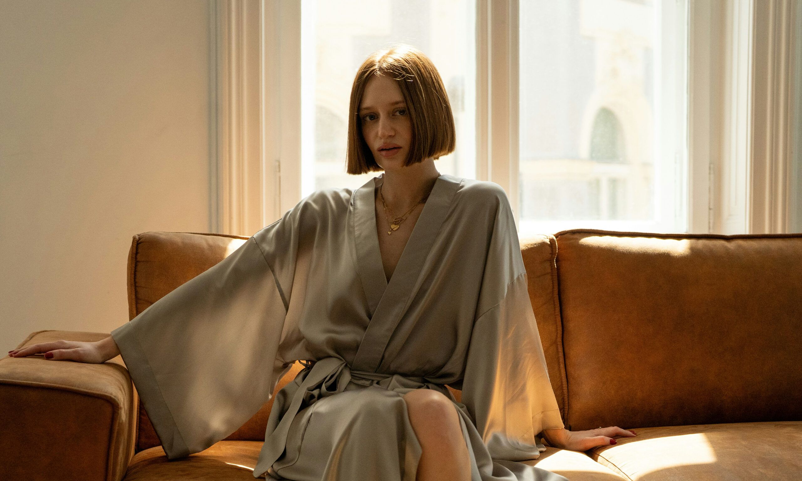woman with short hair sitting on couch in a silk robe