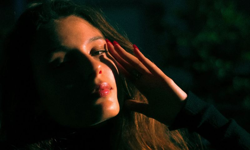 woman sitting in dark with hand on her face