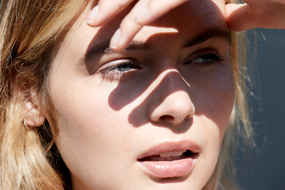 woman in the sun with hands shielding her eyes