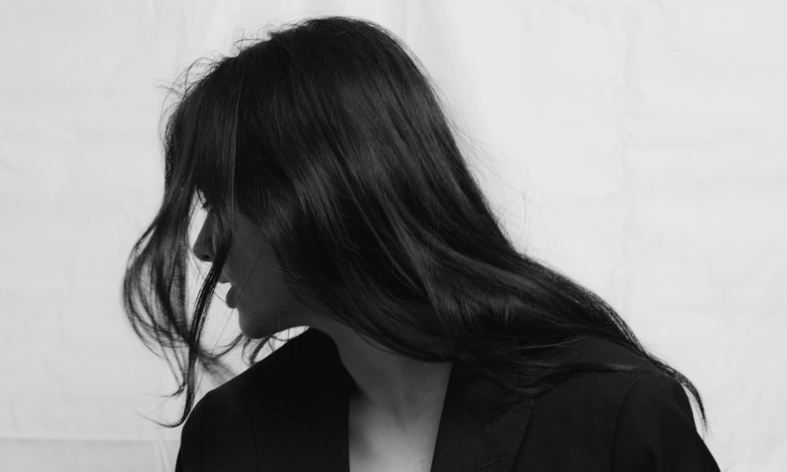 black and white image of woman looking to the side with long hair covering her face