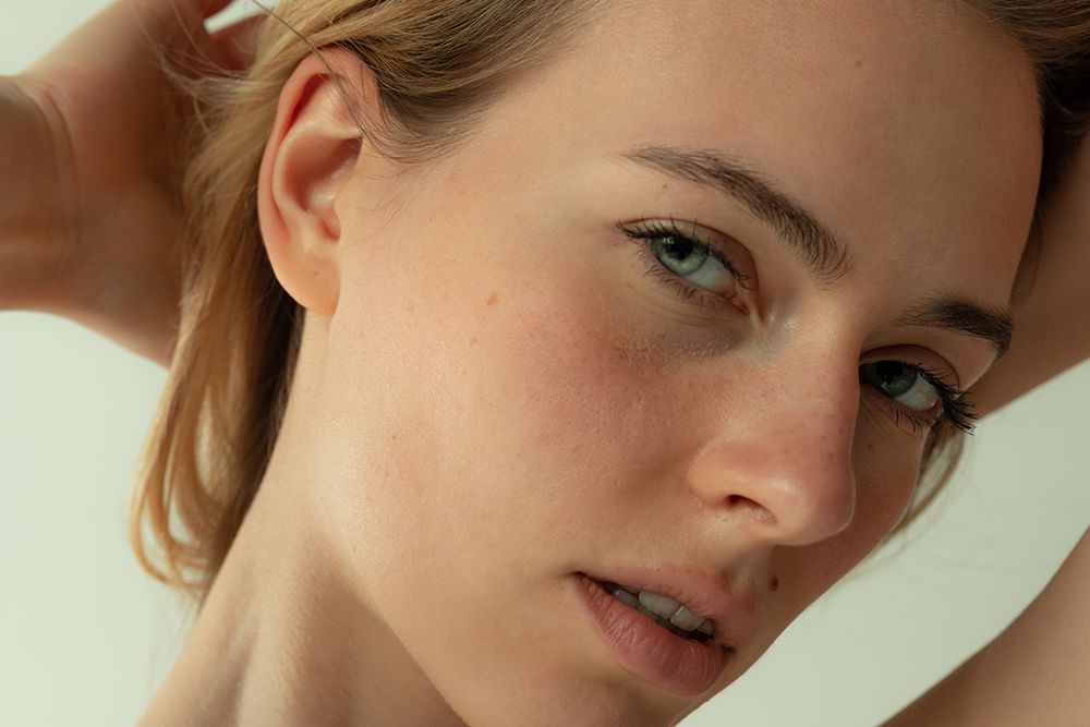Portrait of young beautiful woman with light green eyes and blonde hair posing isolated over grey studio backgrouond. Concept of beauty, body and skin care, health, naturality, cosmetics, ad