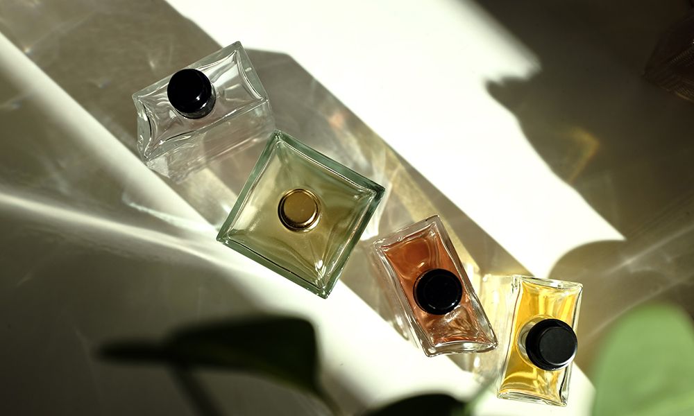 four perfume bottles on white background, seen in a sunlight and shadows