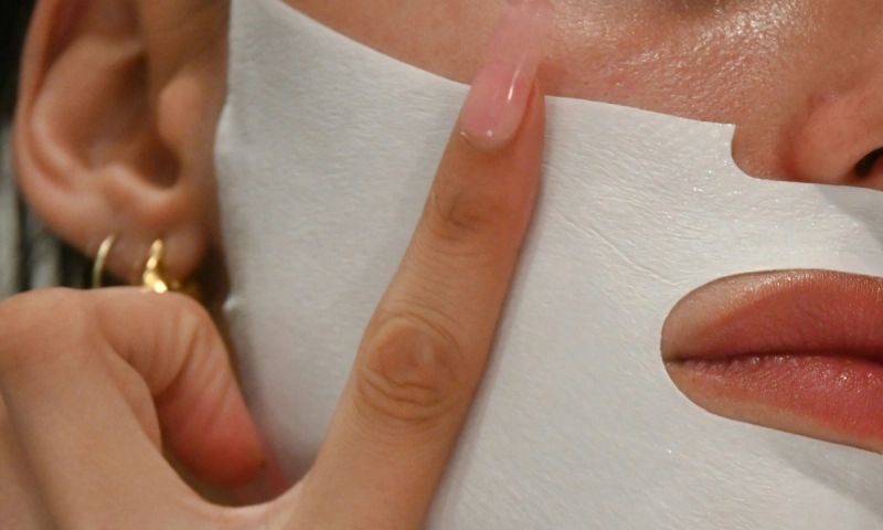zoomed in image of woman applying sheet mask to lower face