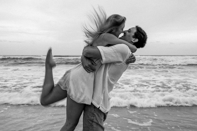 black and white photo of couple kissing on beach