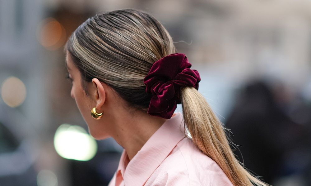 Close-up detail view of a sleek ponytail with purple hair scrunchie.