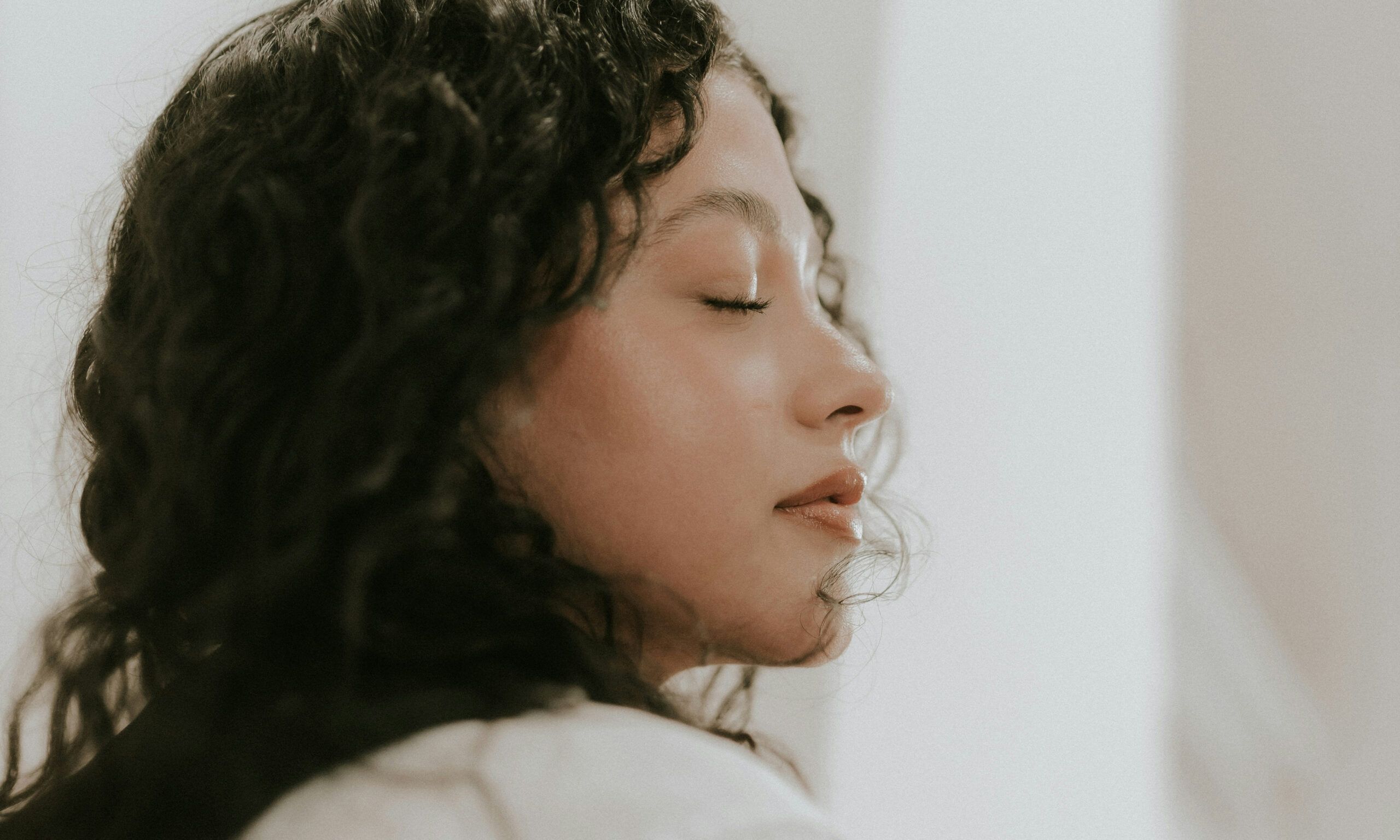 woman with curly hair closing her eyes