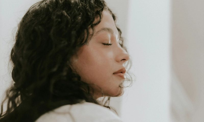 woman with curly hair closing her eyes