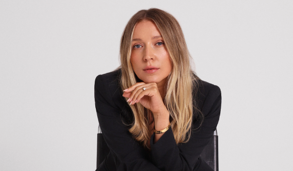 Margarita Nazarenko sits in a black chair wearing a black blazer, resting her chin on her hand.