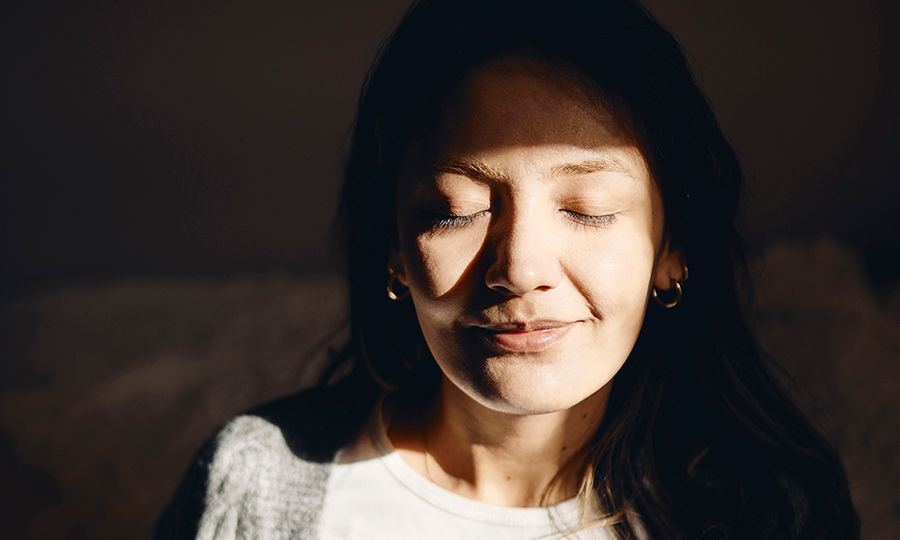 Smiling young woman with eyes closed at home