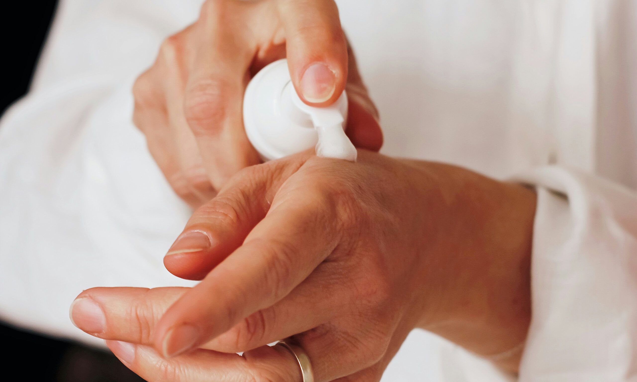 person pumping cream onto hand
