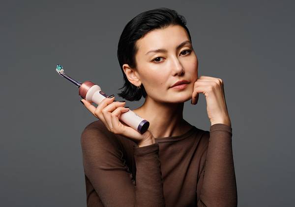 A model with a short dark bob holds the Dyson CameraJet electric toothbrush.