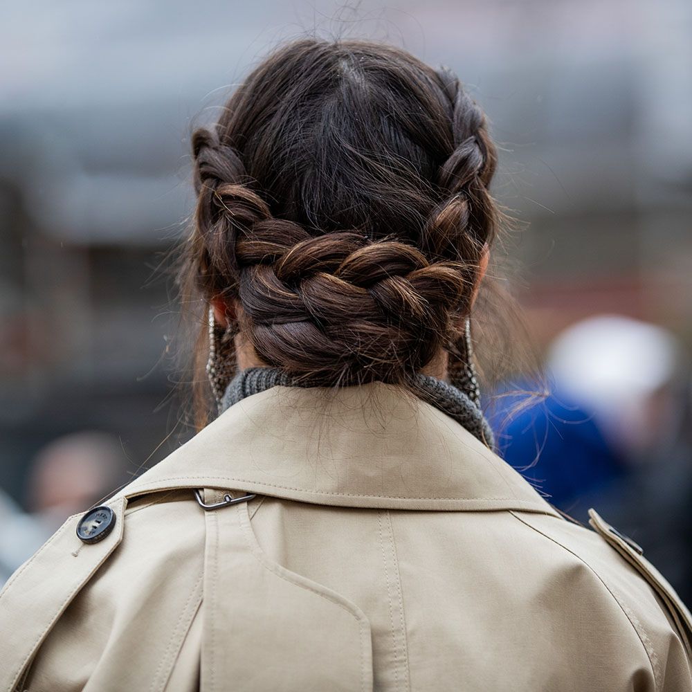 Back view of woman with french braid bun hairstyle wearing a trench coat