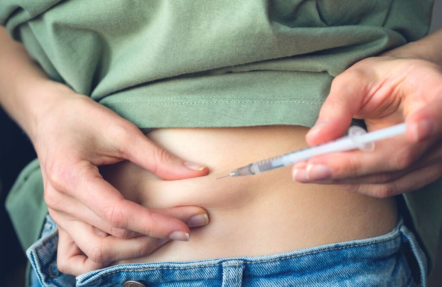 woman giving herself an injection in the abdomen