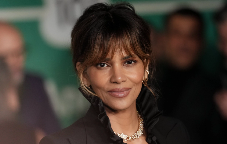 Halle Berry at a red carpet event, wearing a black ruffled blouse and diamond necklace.