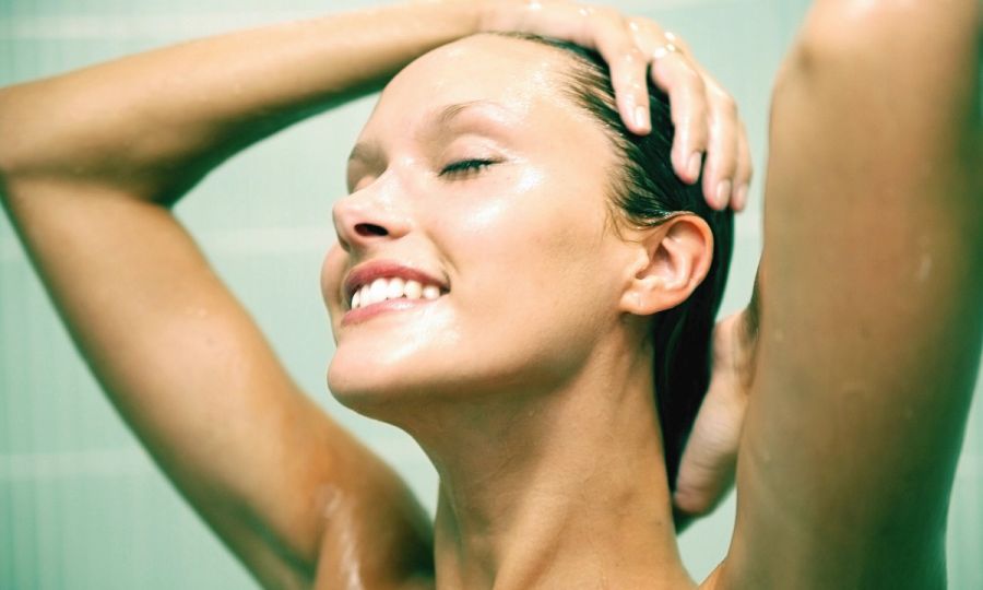 woman smiling while rinsing hair in the shower