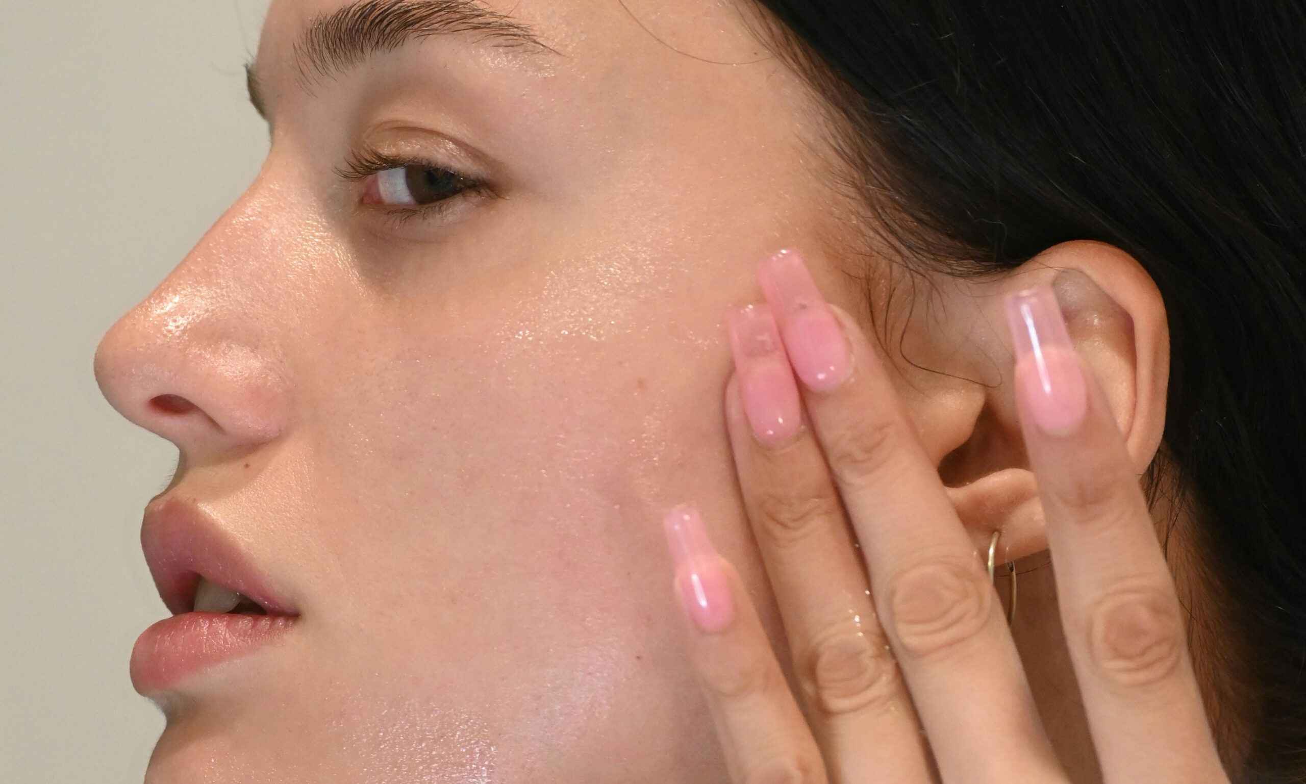 side profile close up of woman touching cheek and face