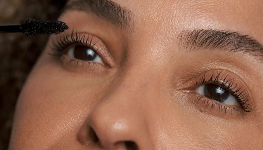 A close up of a woman's upper half of her face as she puts on mascara