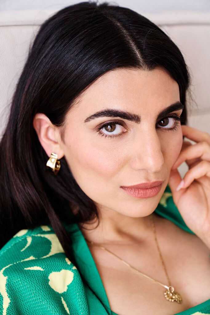 Close up photo of Claudia Doumit in green dress and wearing gold jewlery